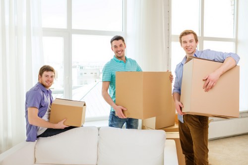 Professional movers carrying furniture through a shared hallway in St Johns Wood